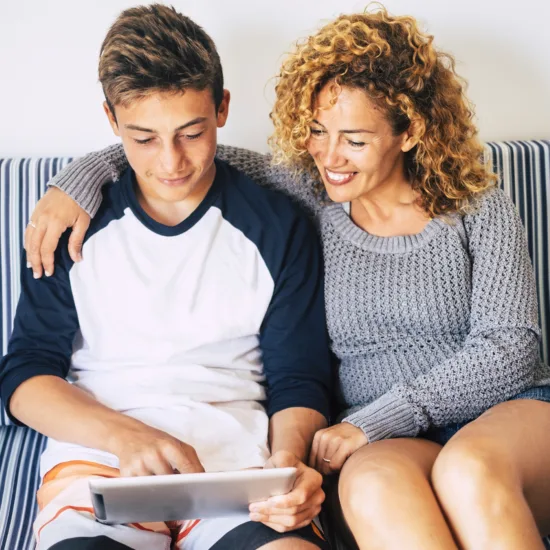 Mãe e filho olhando juntos um tablet no sofá