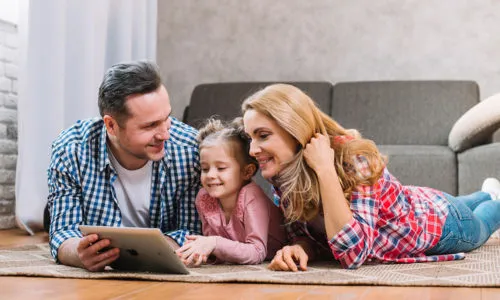 Família reunida no tapete da sala usando um tablet